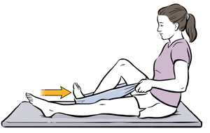 Woman seated on exercise mat using towel around foot to do heel slide exercise.