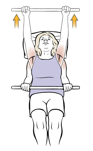 Woman lying on back holding a dowel and lifting it over head in shoulder exercise. 