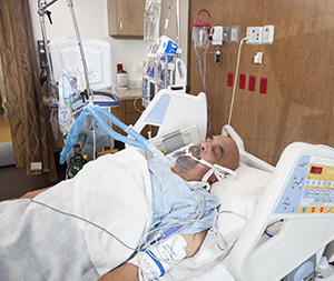 Intubated man in intensive care unit bed.