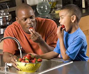 Man and boy eating strawberries.