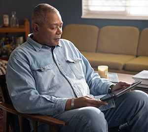 Man sitting in chair, using electronic tablet.